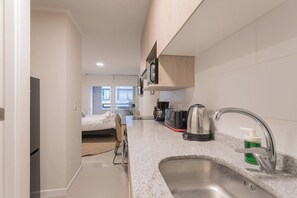 A modern kitchen with a sink, coffee maker, and kettle. - Santa Rosa Apartments by Andes (Santiago)