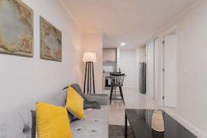 A modern living room with a sofa, a coffee table, and a lamp. - Santa Rosa Apartments by Andes (Santiago)