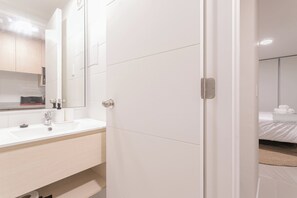 A hotel room with a white bathroom, a sink, and a mirror. - Santa Rosa Apartments by Andes (Santiago)