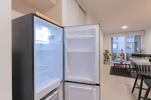 A modern kitchen with a built-in refrigerator, a dining area with a table and chairs, and a view of the outside through a window. - Santa Rosa Apartments by Andes (Santiago)