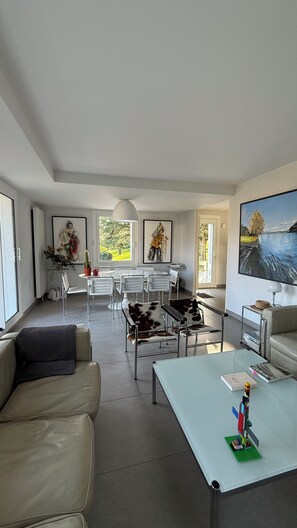A spacious living area with a dining table, chairs, a sofa, and a coffee table. - Family Home on Lake Annecy (Saint-Jorioz)
