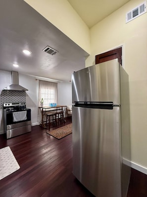 A compact kitchen with a stainless steel refrigerator, a gas stove, and a built-in oven.