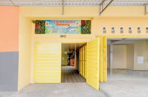 A building entrance with a yellow gate, a sign above reading 'TERIMA KOST Blessing,' and a number '99C' on the wall.