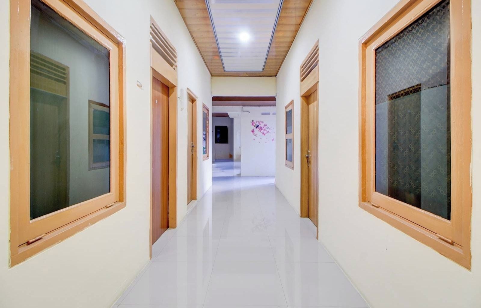 A hallway with doors on both sides, a tiled floor, and a ceiling with recessed lighting.