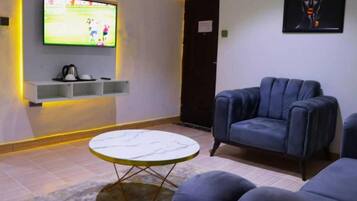 A living room with a television, a sofa, and a small table.
