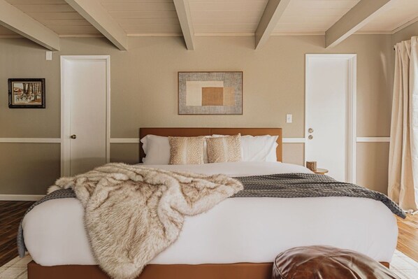 A bedroom with a large bed, a headboard, a wall-mounted artwork, and a door with a curtain. - Deer & Pine - Hot tub, Dogs ok, Large Patio (Big Bear Lake)