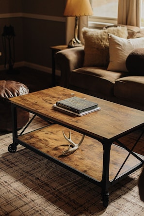 A wooden coffee table with metal legs and a book on it, placed in a cozy room with a patterned rug. - Deer & Pine - Hot tub, Dogs ok, Large Patio (Big Bear Lake)