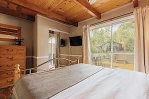 Quarto com cama, cómoda de madeira e televisão na parede.