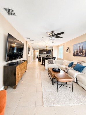 A modern living room with a flat-screen TV, a sofa, a coffee table, and a dining area in the background. - The Jedi Lounge/Pool/Spa/Arcade & Starry Night (Davenport)