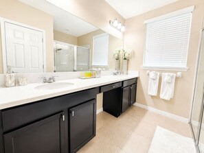 Un bagno moderno con due lavandini, uno specchio grande e una doccia a filo pavimento.