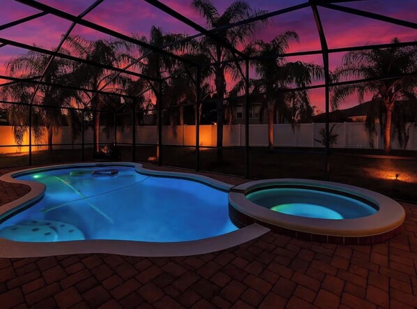 Piscina com design curvo, ladeada por um terraço de tijolos.