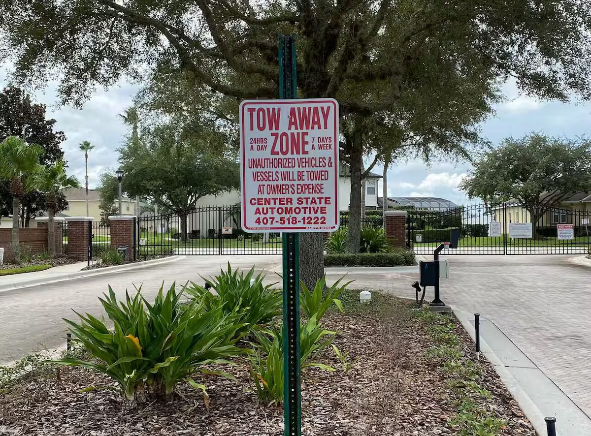 A tow-away zone sign with a contact number for the Center State Automotive.