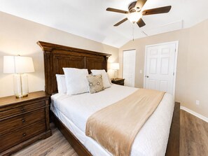 A bedroom with a wooden headboard, a bed with white bedding, two bedside tables with lamps, and a ceiling fan. - The Jedi Lounge/Pool/Spa/Arcade & Starry Night (Davenport)
