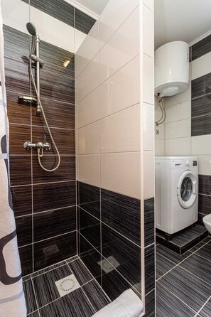 A bathroom with a shower, a washing machine, and a toilet. - Holiday apartment SANELA with private pool (Hlapa)