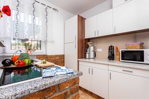 A kitchen with a granite countertop, white cabinets, a microwave, and a coffee maker. - Holiday apartment SANELA with private pool (Hlapa)