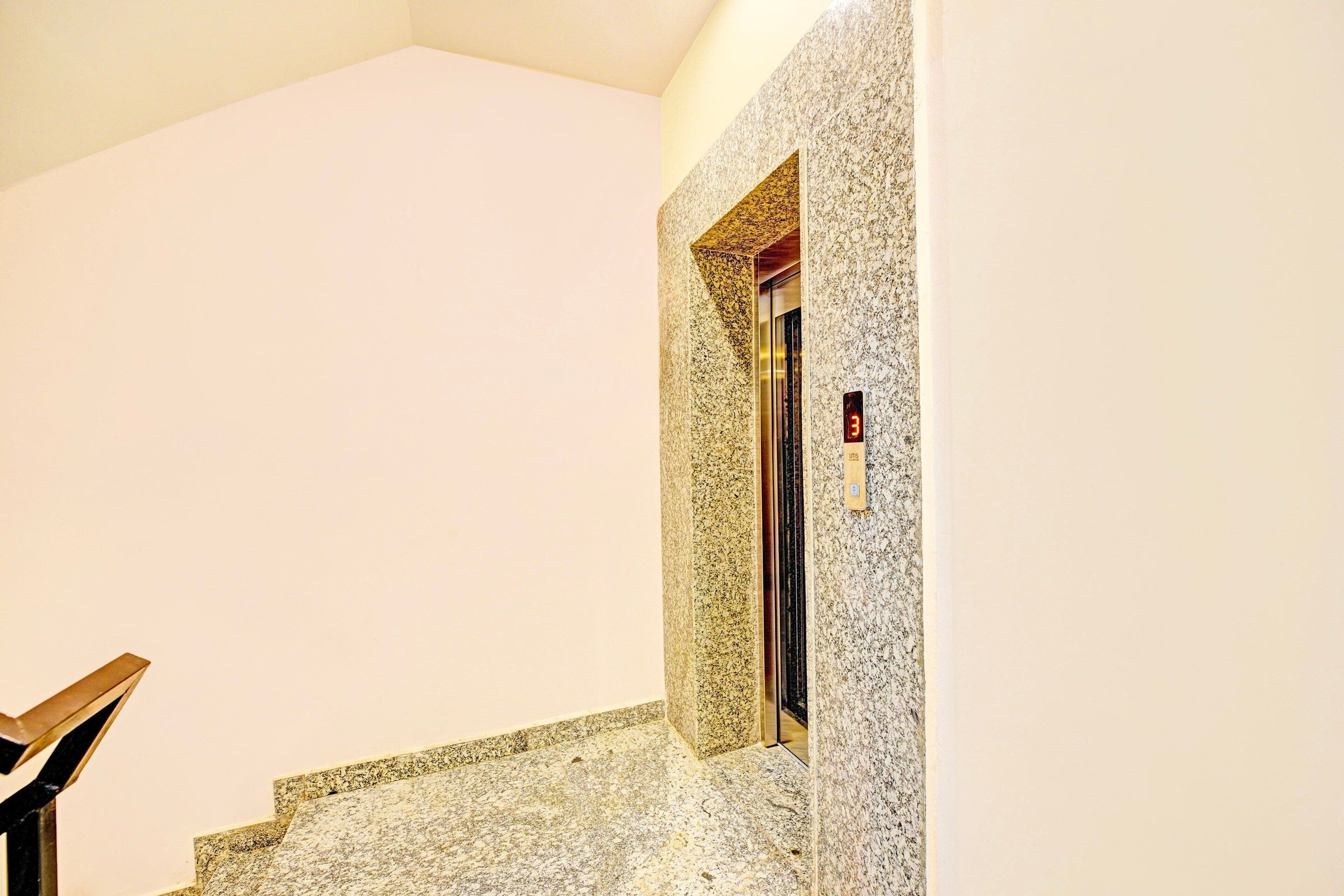 A staircase with a granite finish leading to an elevator.