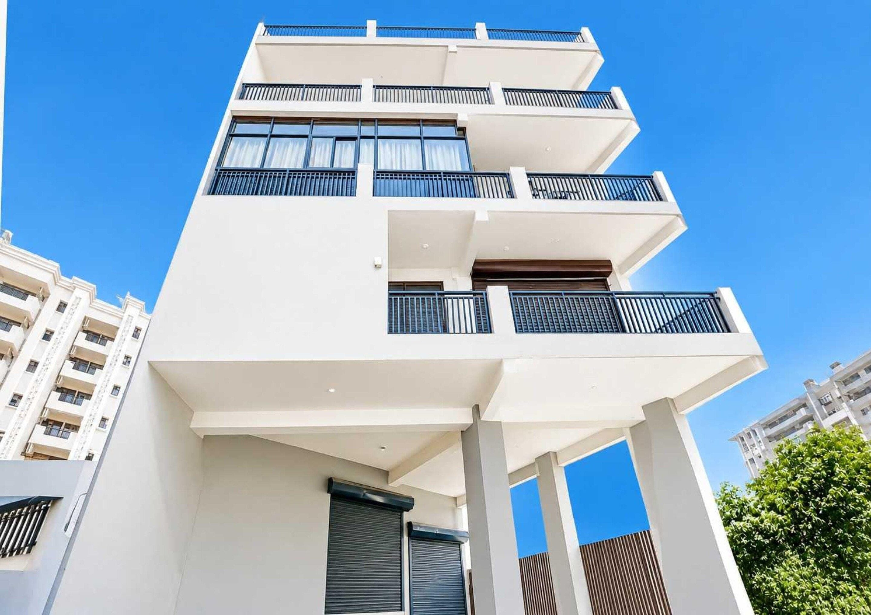 A multi-story building with balconies, large windows, and a clear sky.