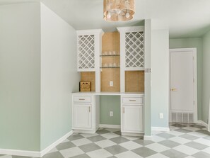 A room with a checkered floor, white cabinetry, and a hanging light fixture. - Quail Creek Home | Koi Pond, 2 Kings, EV Charger (Oklahoma City)