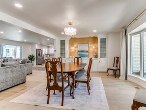 A spacious living area with a dining table, sofas, and a kitchen in the background. - Quail Creek Home | Koi Pond, 2 Kings, EV Charger (Oklahoma City)