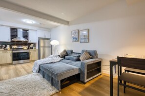 A modern kitchen with stainless steel appliances, a dining area with a bench, and a sofa with a throw blanket. - Welcome to Sapphire Inn which is 13  minutes from YYC Calgary Airport (Calgary)