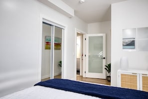 A bedroom with a bed, a white wardrobe, a door with frosted glass, and a white console table. - Welcome to Sapphire Inn which is 13  minutes from YYC Calgary Airport (Calgary)