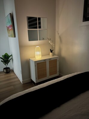 A room with a bedside table, a lamp, a potted plant, and a mirror above the table. - Welcome to Sapphire Inn which is 13  minutes from YYC Calgary Airport (Calgary)