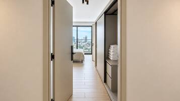 A hotel corridor with a bed, a wardrobe, and a view of the city.