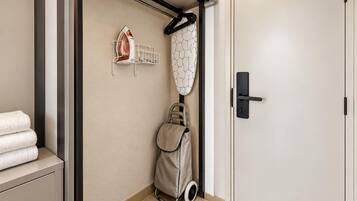 A bathroom with a towel rack, an iron, and a wheelchair.