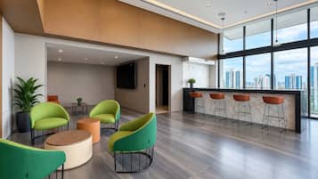 Un intérieur moderne avec un espace bar, des sièges et une grande fenêtre donnant sur la ville.