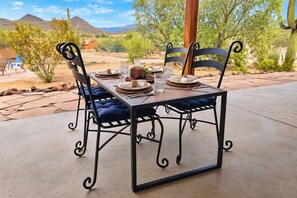 An outdoor dining table with chairs, set with plates, glasses, and a centerpiece. - Cave Creek Desert Dream — 3BR Main House (Cave Creek)