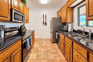 A modern kitchen with wooden cabinets, stainless steel appliances, and a tiled floor. - Cave Creek Desert Dream — 3BR Main House (Cave Creek)