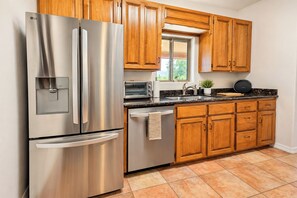 A kitchen with stainless steel appliances, wooden cabinets, a window, and a countertop with a sink and a toaster. - Cave Creek Desert Dream — 3BR Main House (Cave Creek)