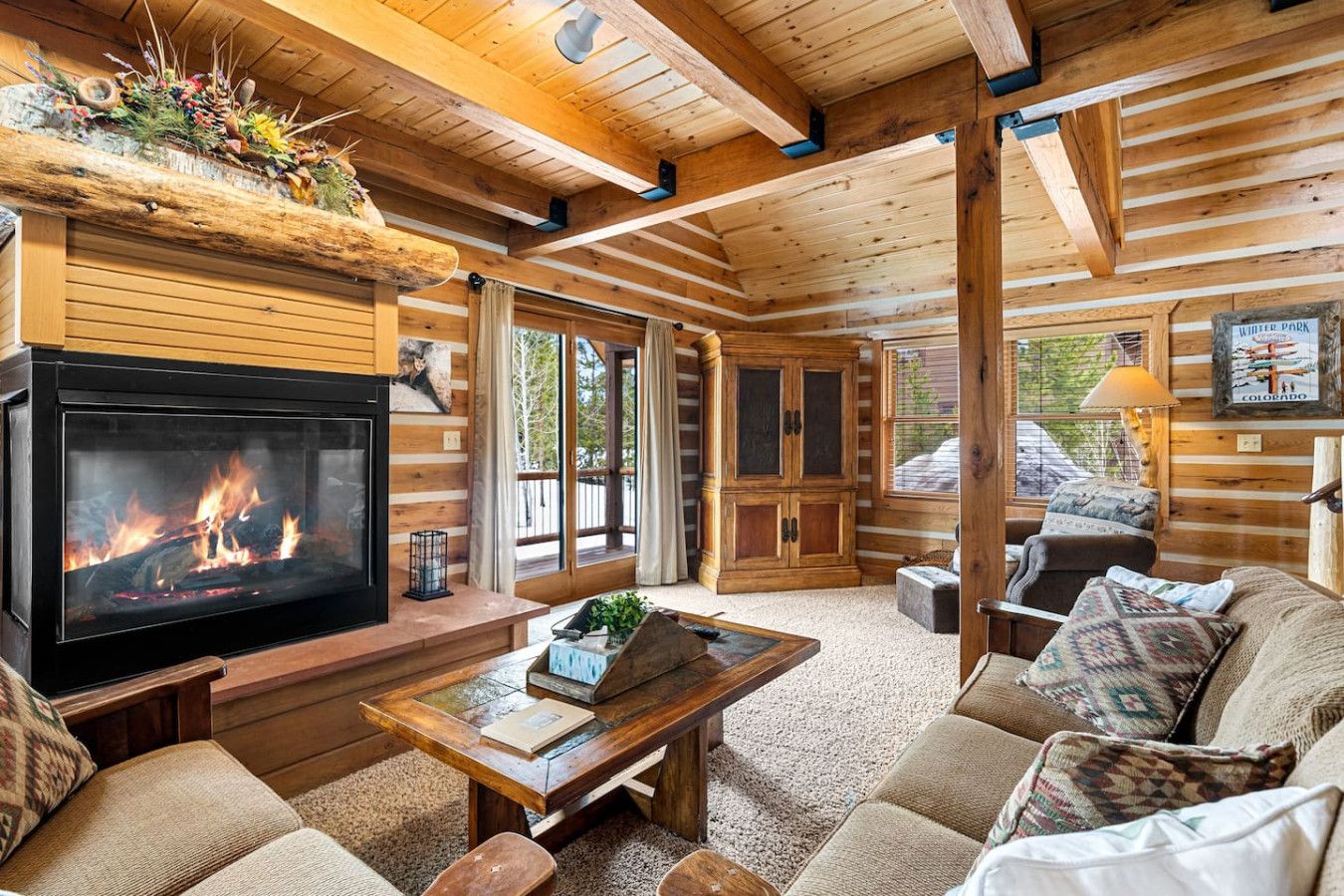 L’intérieur d’un chalet confortable, avec une cheminée, des meubles en bois et une grande fenêtre.