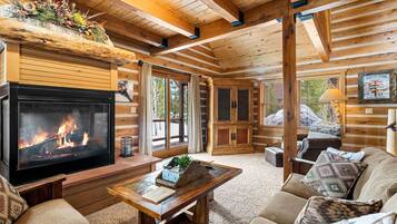 L’intérieur d’un chalet confortable, avec une cheminée, des meubles en bois et une grande fenêtre.