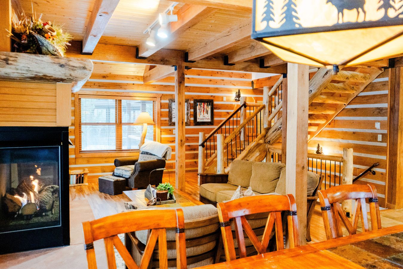 Ein gemütliches Blockhaus-Interieur mit Kamin, Holzmöbeln und einer Wendeltreppe.