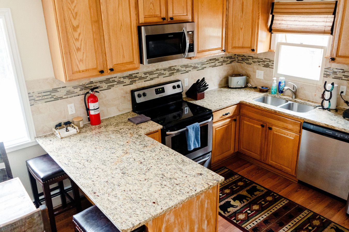 A kitchen with wooden cabinets, granite countertops, a stainless steel microwave, a stove, and a dishwasher.