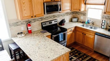 A kitchen with wooden cabinets, granite countertops, a stainless steel microwave, a stove, and a dishwasher.
