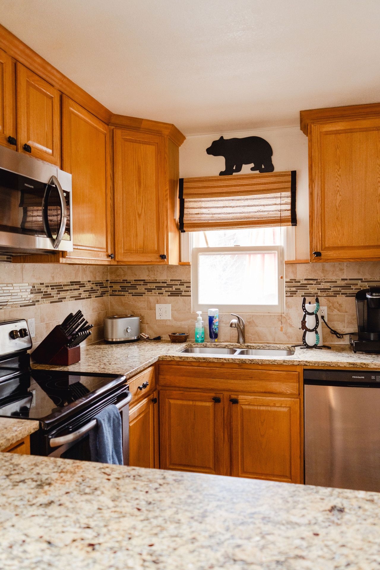 Una cocina con armarios de madera, microondas, tostadora, lavabo y cafetera.