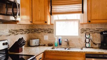 Una cocina con armarios de madera, microondas, tostadora, lavabo y cafetera.
