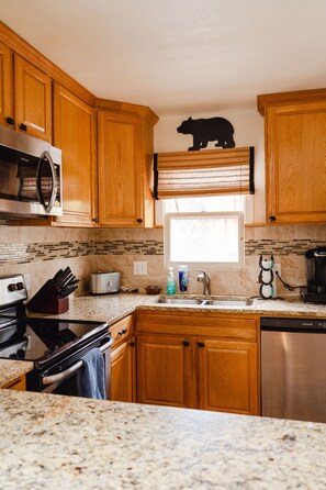 A kitchen with wooden cabinets, a microwave, a toaster, a sink, and a coffee maker.