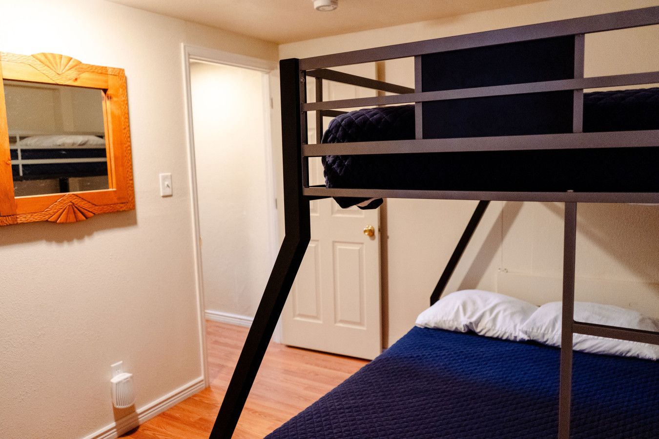 Ein Stockbett mit blauer Matratze und einem Holz-Kopfteil.
