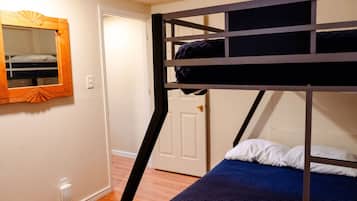 Ein Stockbett mit blauer Matratze und einem Holz-Kopfteil.