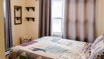 A bedroom with a bed, curtains, a window, and a mirror.