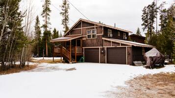 A two-story wooden cabin with a porch, a garage, and a covered outdoor area.