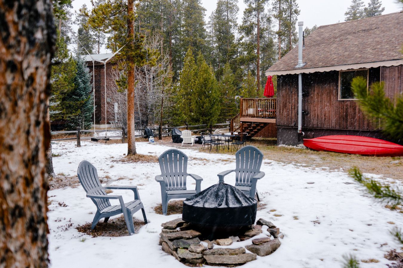 Eine Holzhütte mit Terrasse, umgeben von verschneitem Gelände und Bäumen.