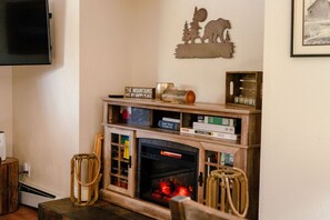 A cozy living room with a fireplace, books, and a bear silhouette decoration.