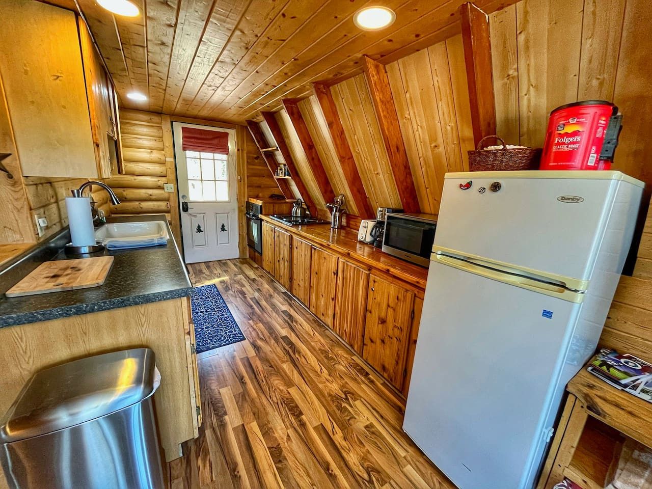 Une cuisine de style rustique, avec des murs en bois, un réfrigérateur, un évier et un plan de travail en bois.