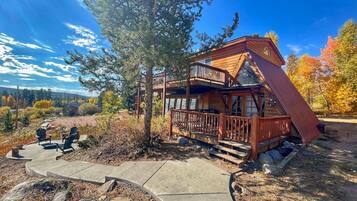 A cabin with a wooden deck, outdoor seating, and a scenic view.