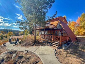 A cabin with a wooden deck, outdoor seating, and a scenic view.