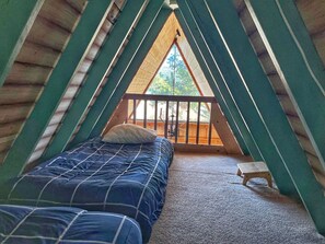 A cozy attic bedroom with a bed, a small stool, and a view of the outdoors. - Relax in the night sky w/ hot tub (Grand Lake)